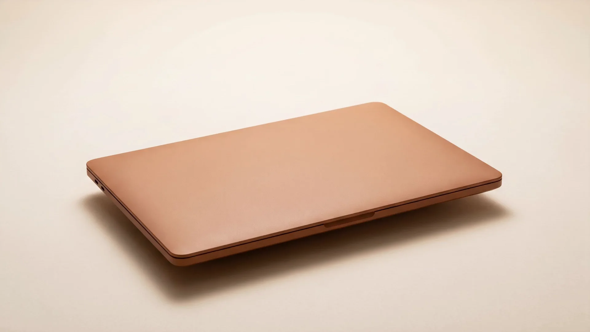 Closed clay-amber laptop sitting on a warm cream desk — the morning state of your local-business control center